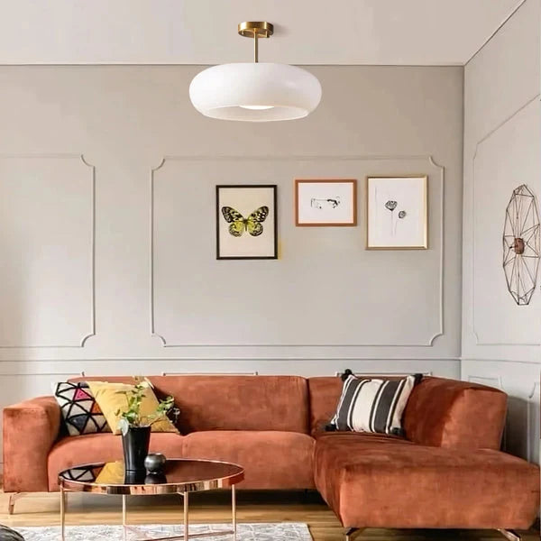 Glas Deckenleuchte im Wohnzimmer über einem Sofa und Bildern an der Wand
