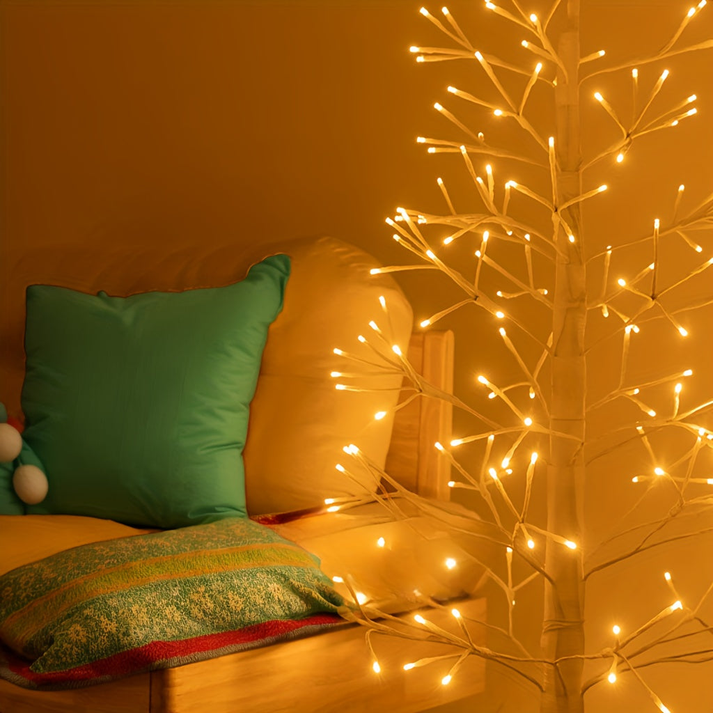 Leuchtende Zweige des LED Baums neben einem Sofa mit grünem Kissen