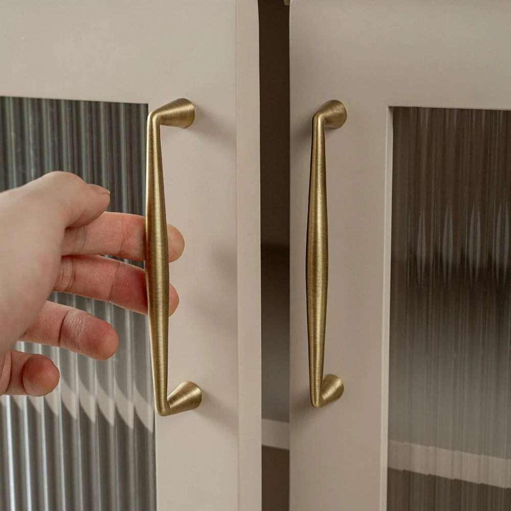 Hand öffnet eine Tür am Griff in Messingoptik
