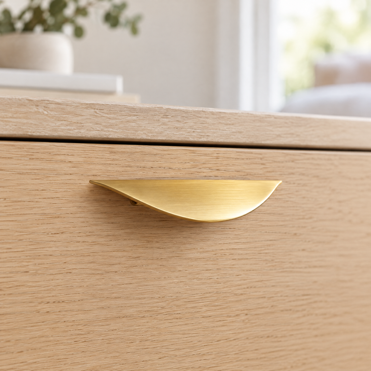 Geschwungener Möbelgriff Gold in Messingoptik, Lochabstand 32 mm, montiert an einer Schublade aus heller Eiche