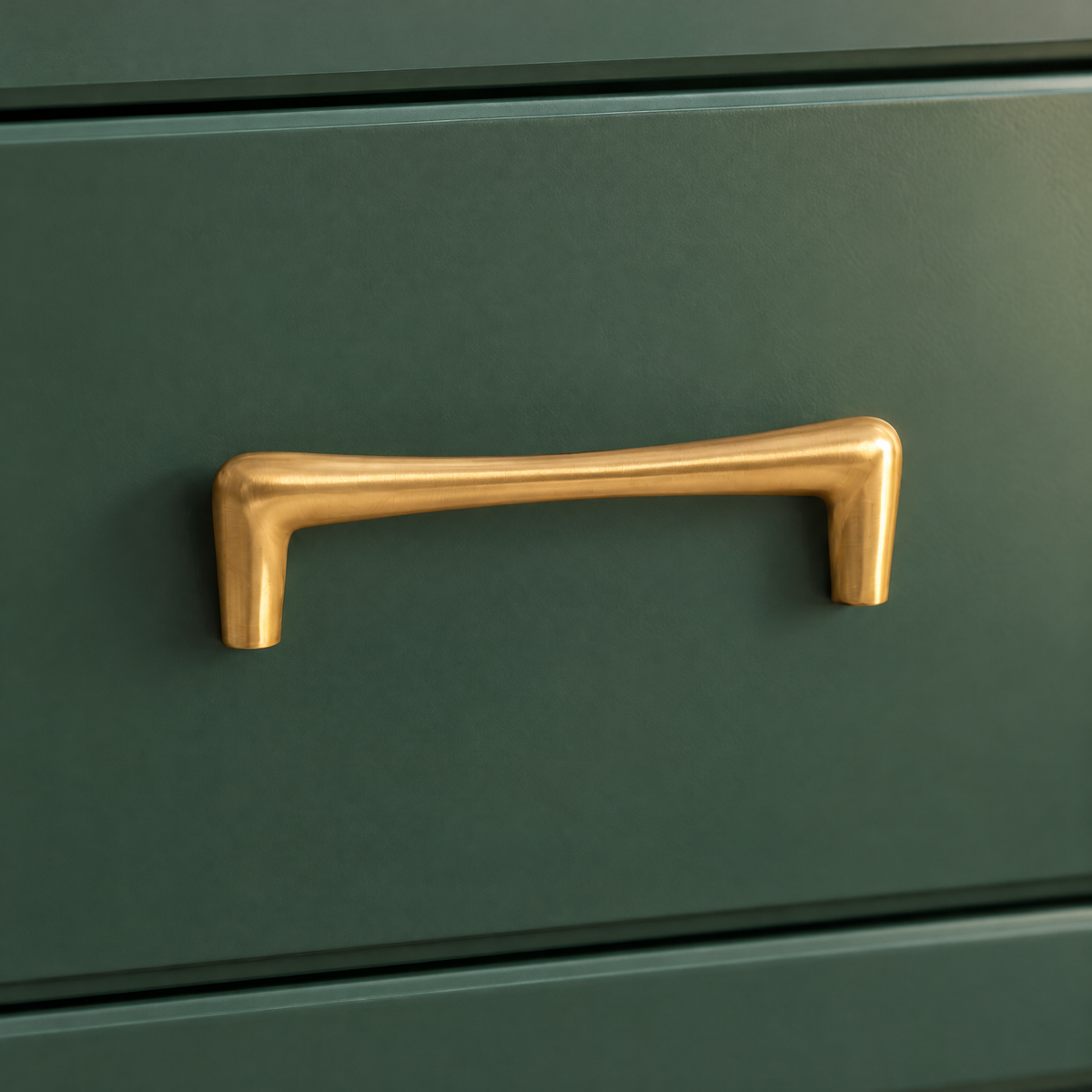 Goldener Möbelgriff in Tropfenform mit Lochabstand 96 mm an einer grünen Schublade