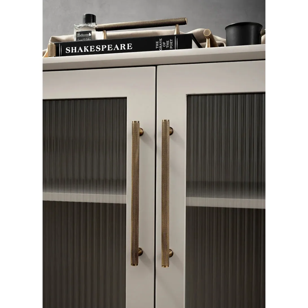 Lange Möbelgriffe mit Rändel an einem Schrank mit Riffelglas