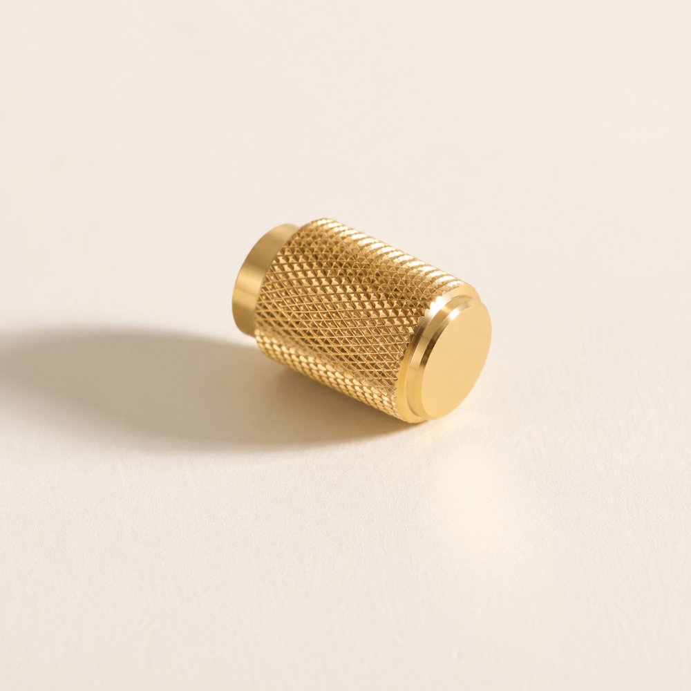 Goldener gerändelter Zylinderknopf liegend auf hellem Hintergrund
