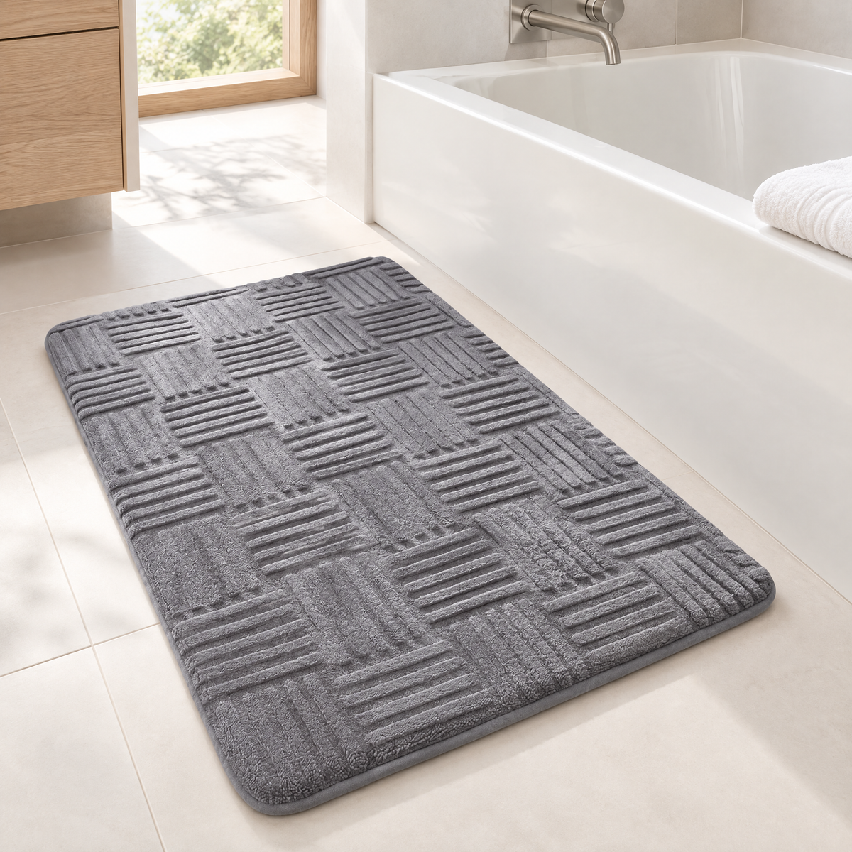 Graue Badematte mit Flechtmuster neben der Badewanne