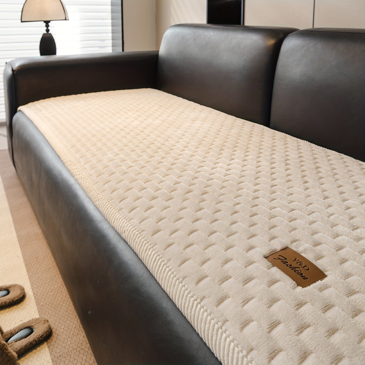 Sofa Überwurf in Creme auf einem dunklen Ledersofa