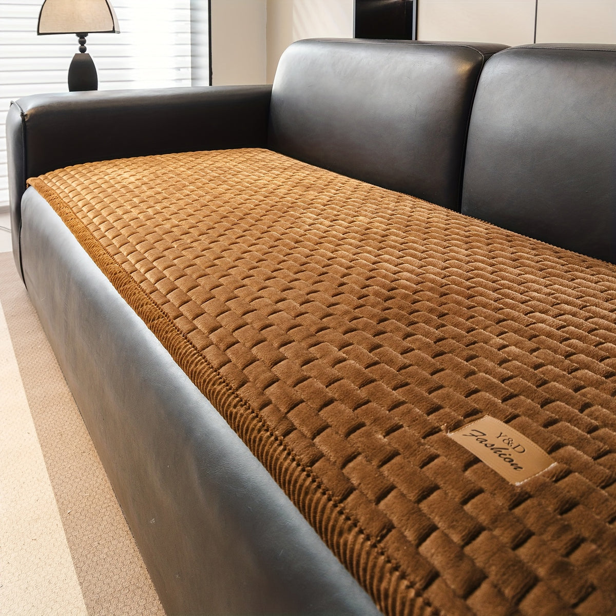 Sofa Überwurf in Karamellbraun auf einem dunklen Ledersofa
