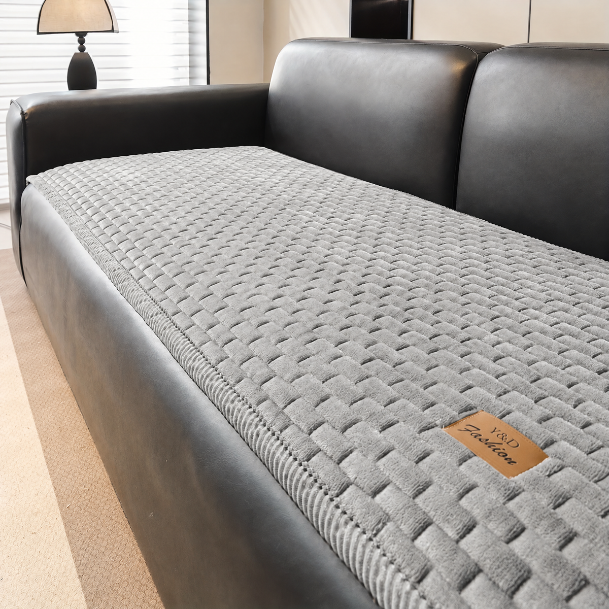 Sofa Überwurf in Hellgrau auf einem dunklen Ledersofa