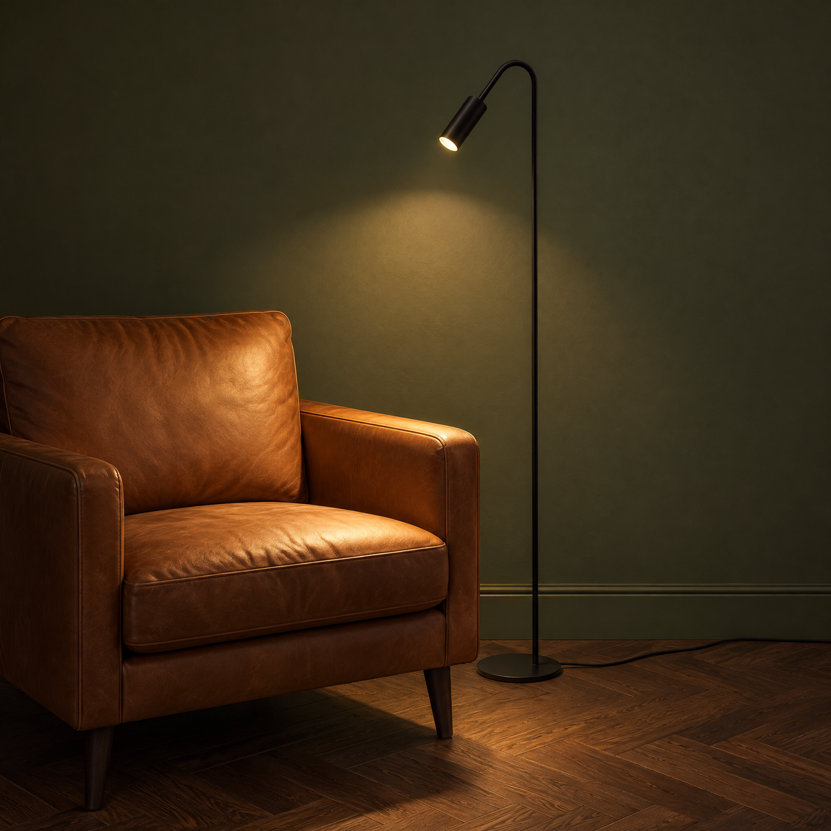 Geschwungene Stehlampe in Schwarz als Leselampe neben einem Ledersessel, eingeschaltet, mit Netzkabel