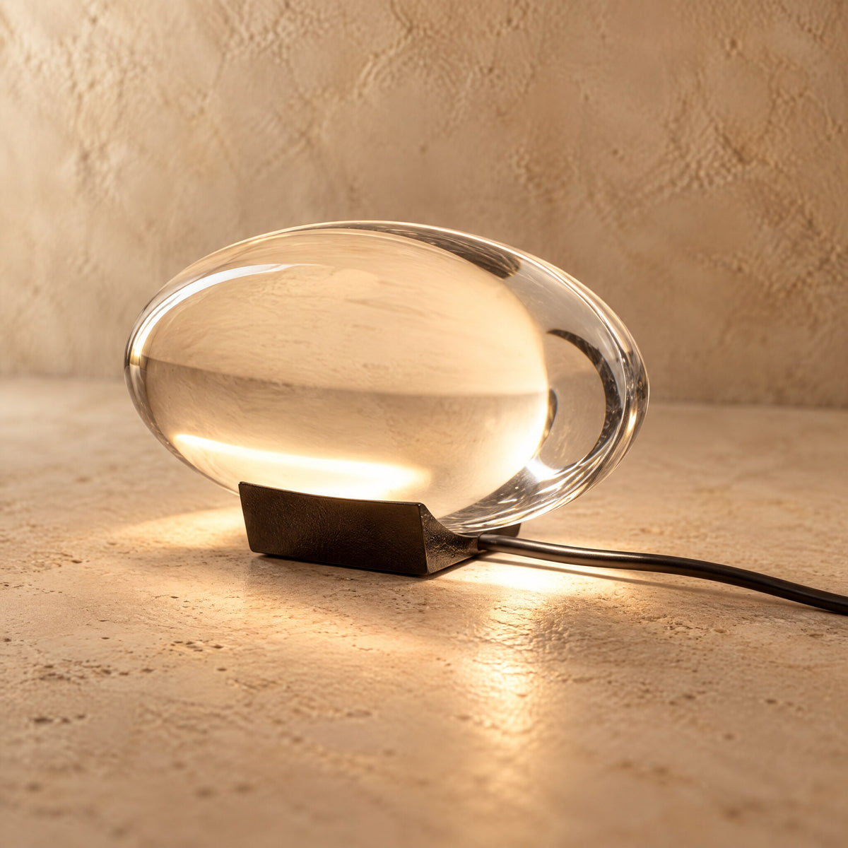 Nahaufnahme der Sunset Lampe: klarer Acrylkörper auf dunklem Metallsockel mit Kabel