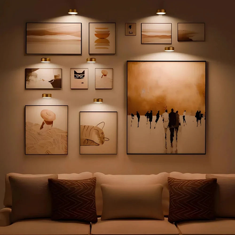 Goldene Bilderleuchten kabellos über einer Bildergalerie im Wohnzimmer