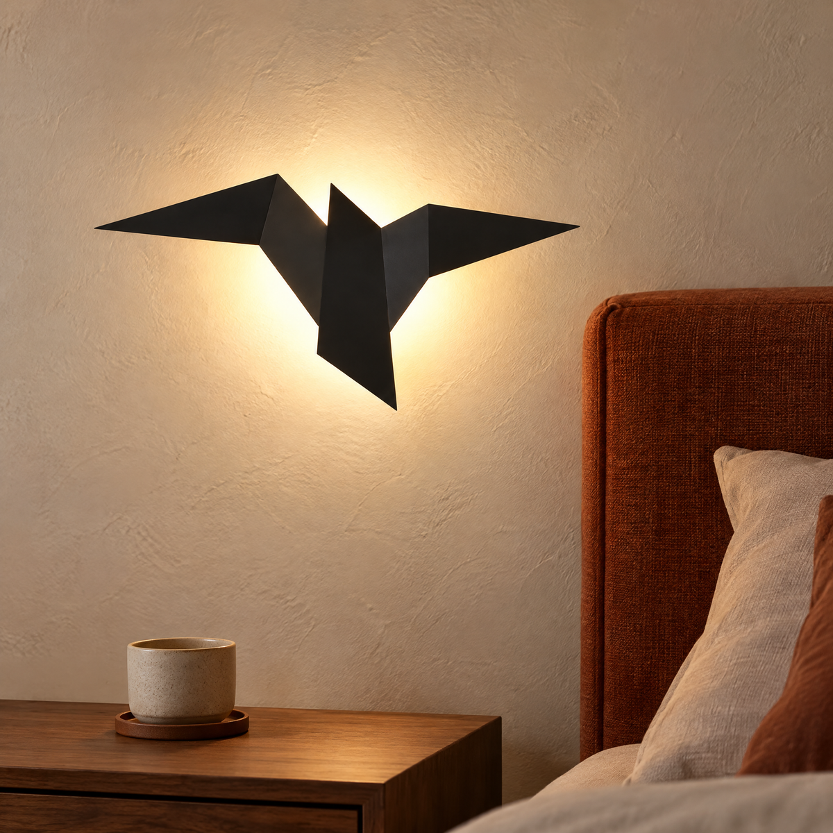 Wandleuchte innen in Vogelform in Schwarz mit warmem Licht über dem Nachttisch im Schlafzimmer