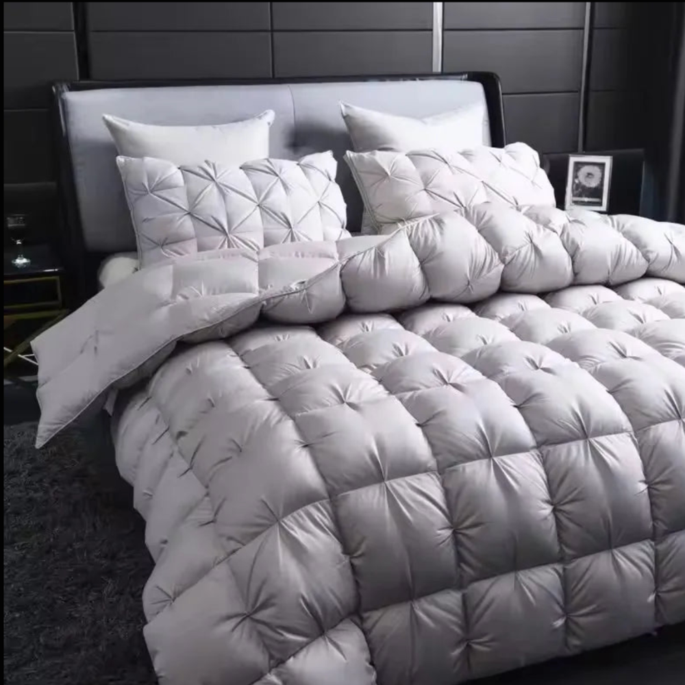 Graue Steppdecke mit dekorativer Raffung auf dem Bett