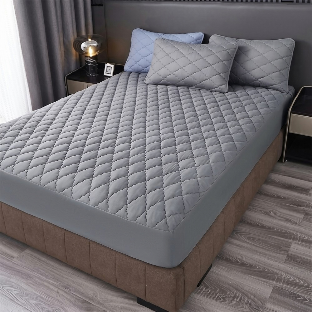 Grauer gesteppter Matratzenschoner auf einem Bett mit Polsterrahmen