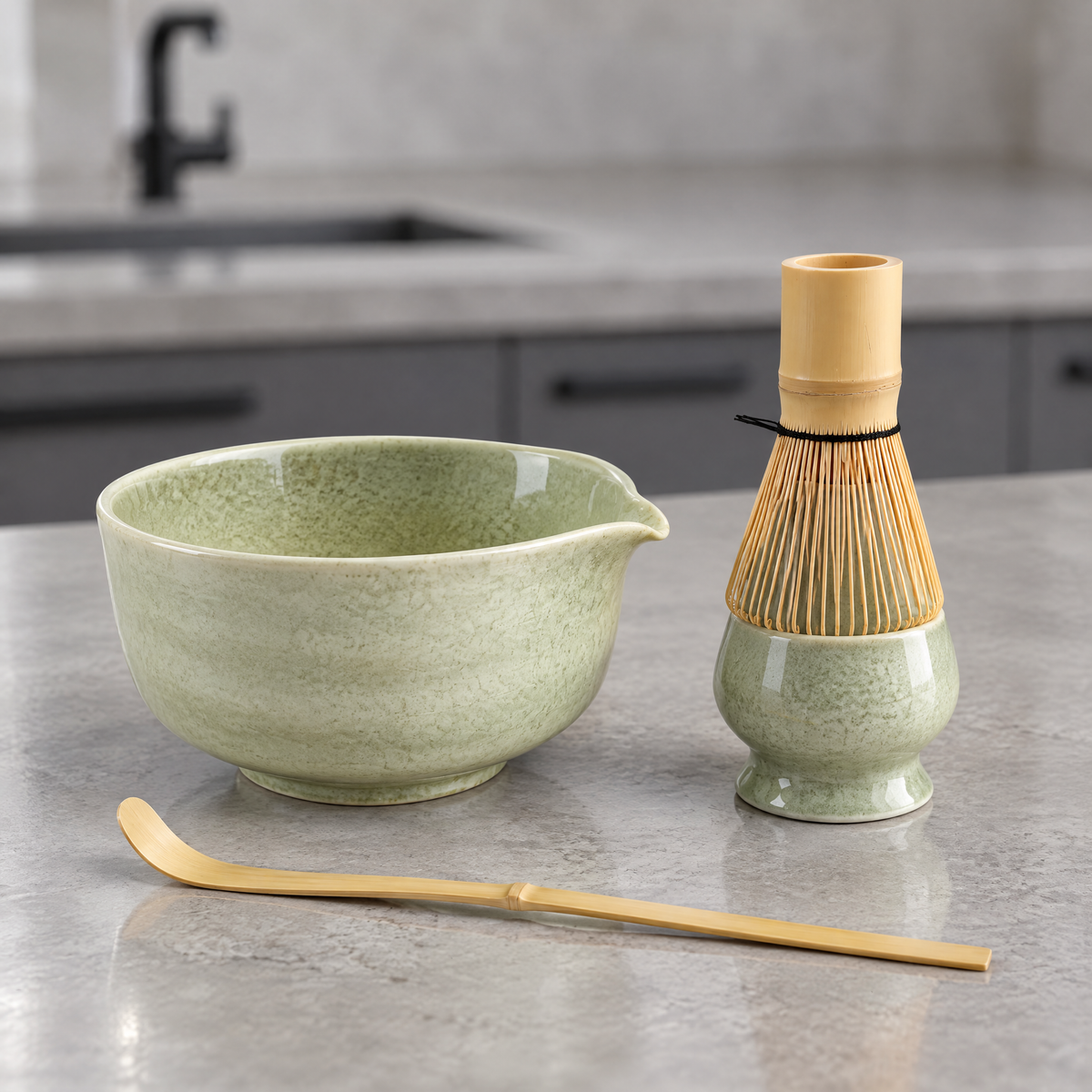 Matcha Set 4-teilig mit blassgrüner Keramikschale, Besenhalter, Bambusbesen und Chashaku auf einer Betonarbeitsplatte