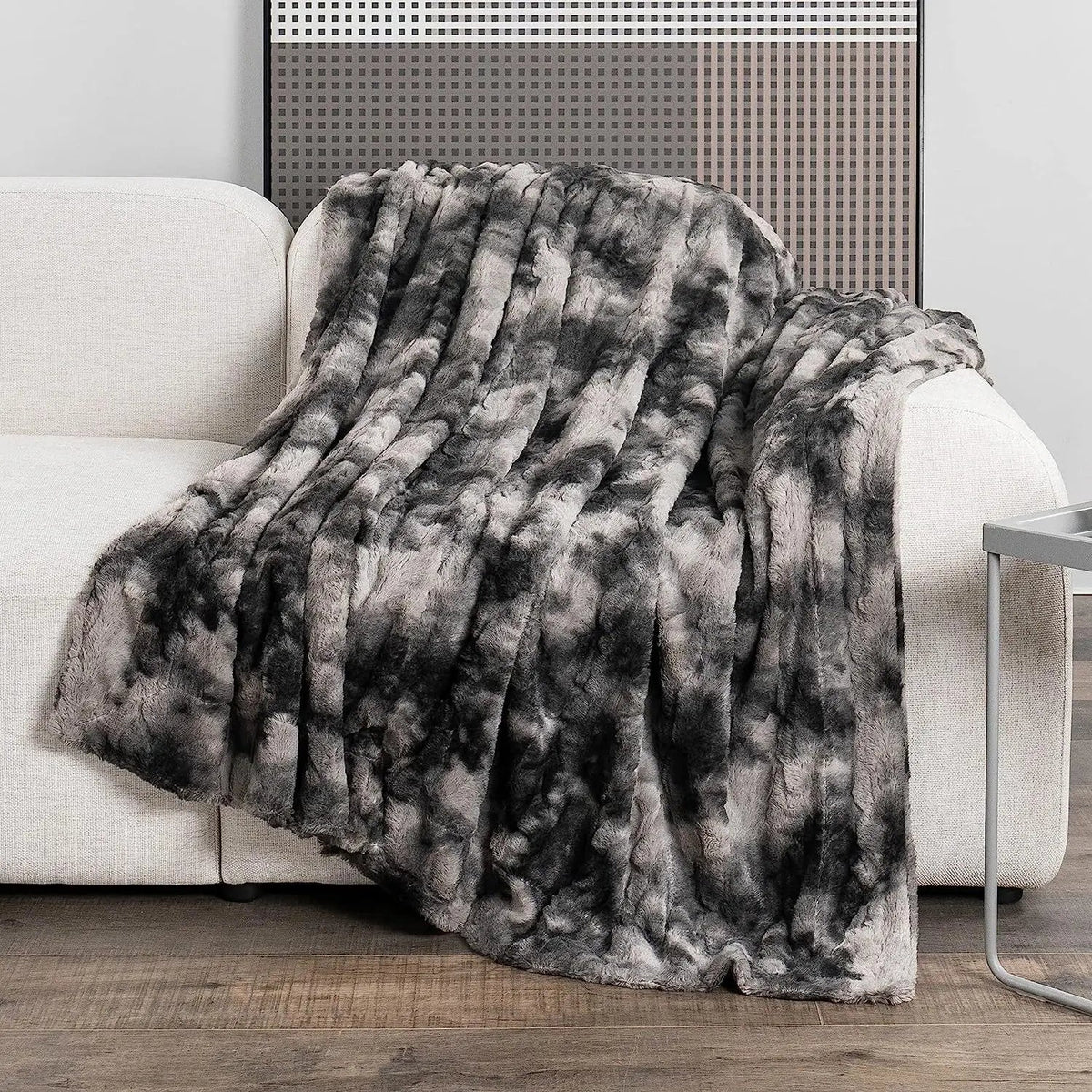 Winterdecke in Felloptik in Anthrazit über der Lehne eines hellen Sofas
