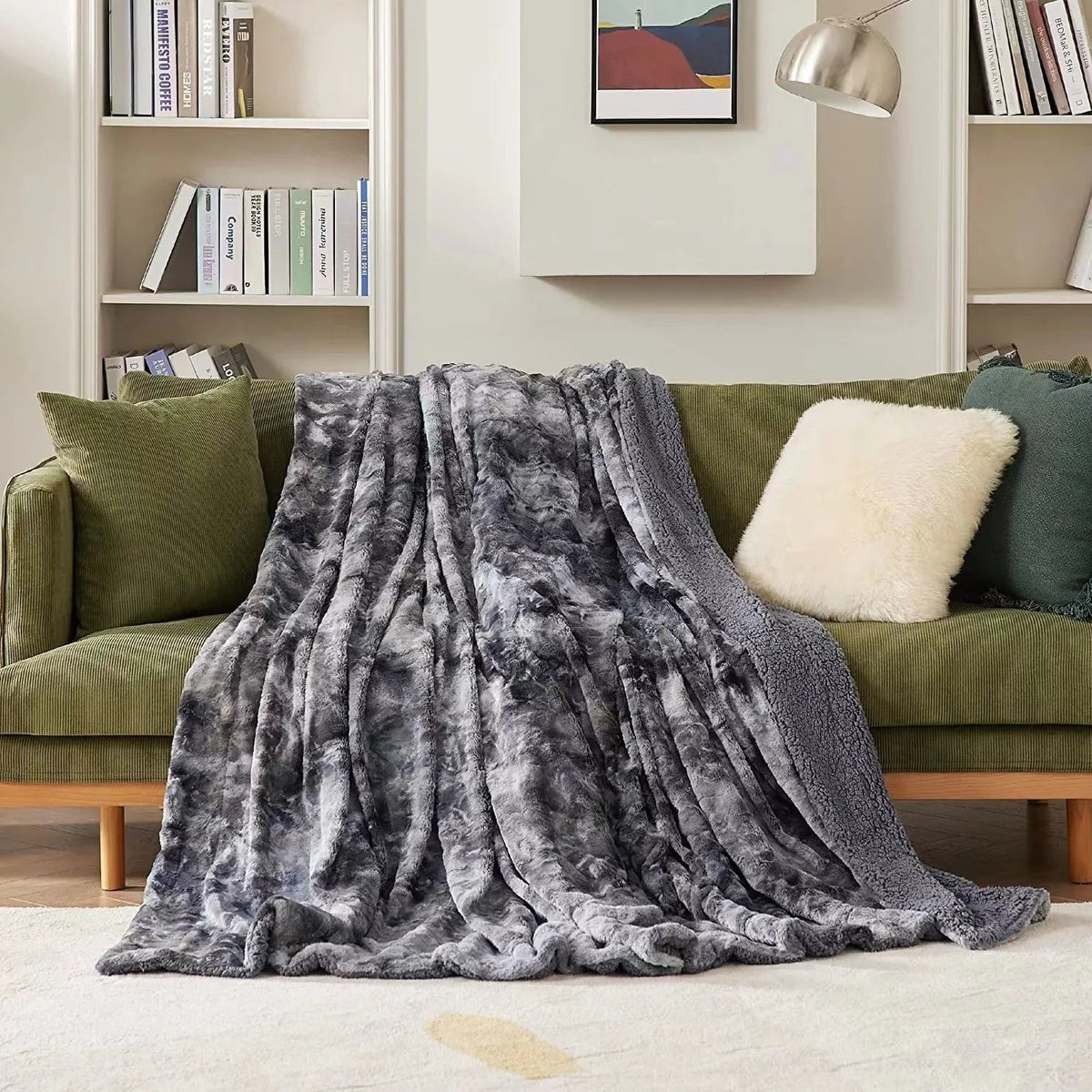 Graue Winterdecke in Felloptik auf einem grünen Sofa im Wohnzimmer