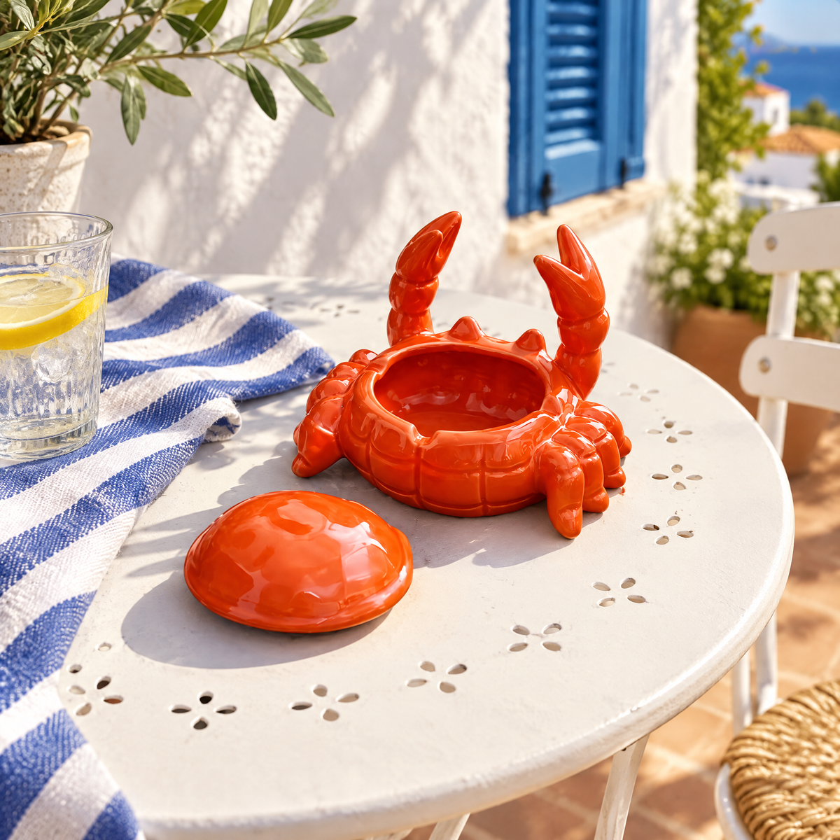 Geöffneter Krebs-Aschenbecher mit abgenommenem Deckel auf einem Bistrotisch im Sommer