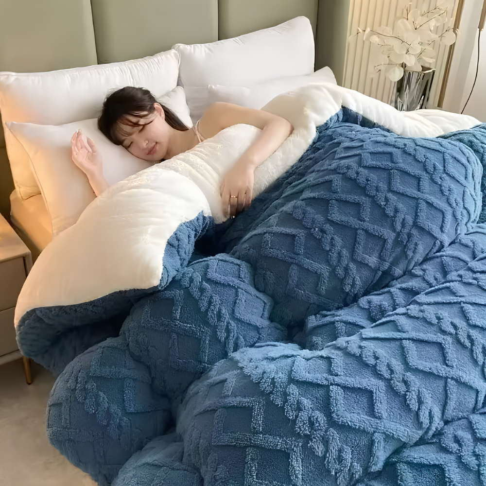 Frau unter einer blauen Winterbettdecke mit Zopfmuster