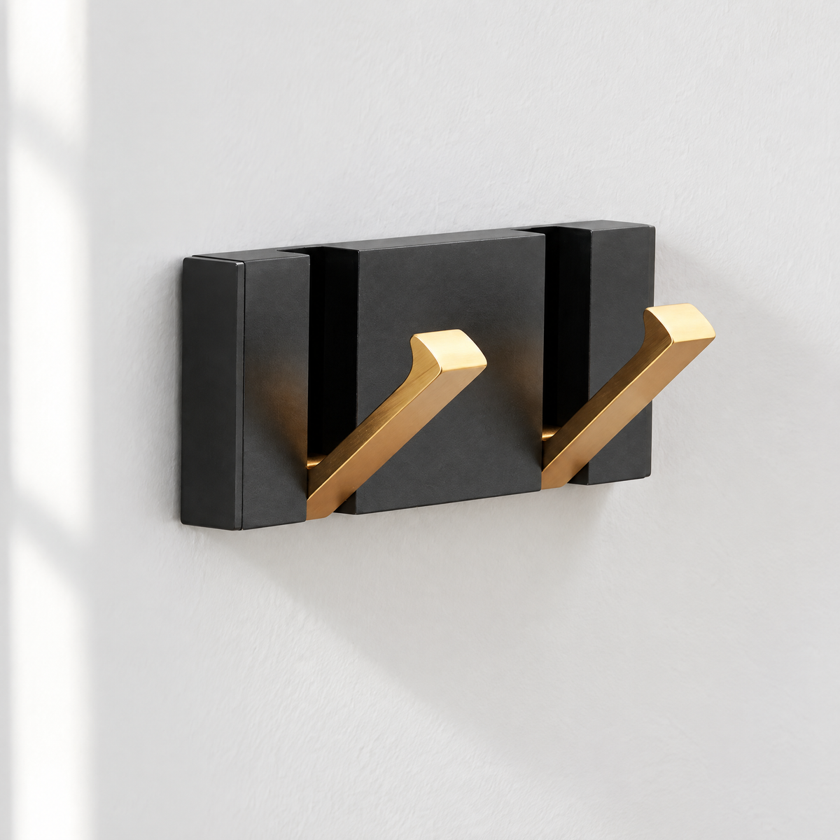 Wandgarderobe mit 2 goldenen Klapphaken auf schwarzer Leiste an einer weißen Flurwand