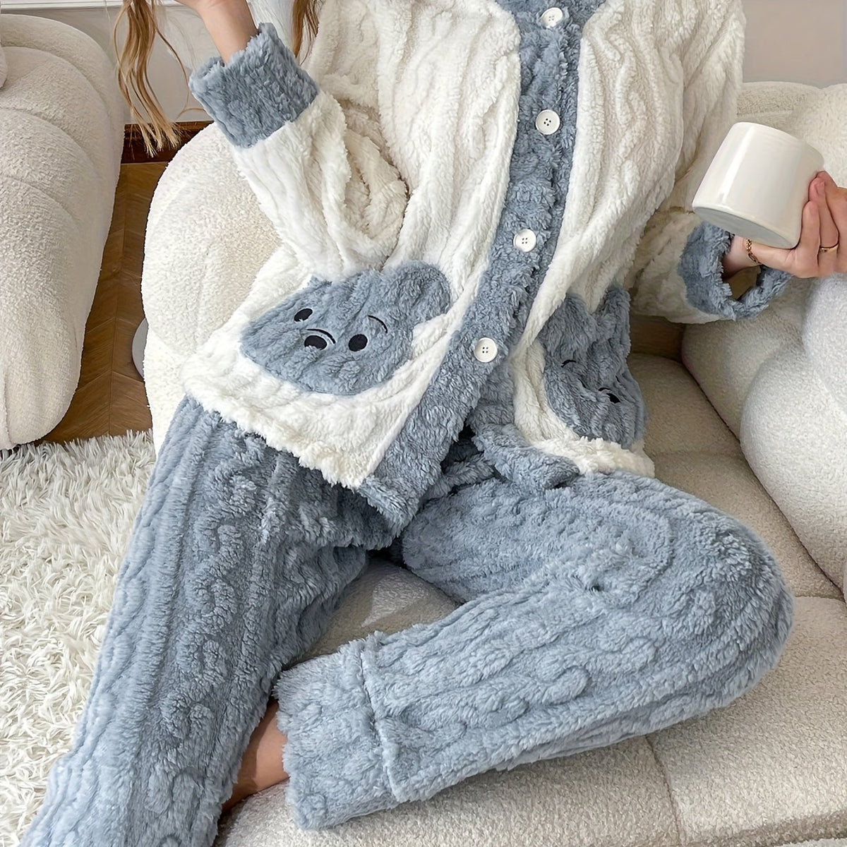 Flanell Pyjama Damen in Creme und Blau mit Bärentaschen, Frau sitzt mit Tasse auf dem Sofa