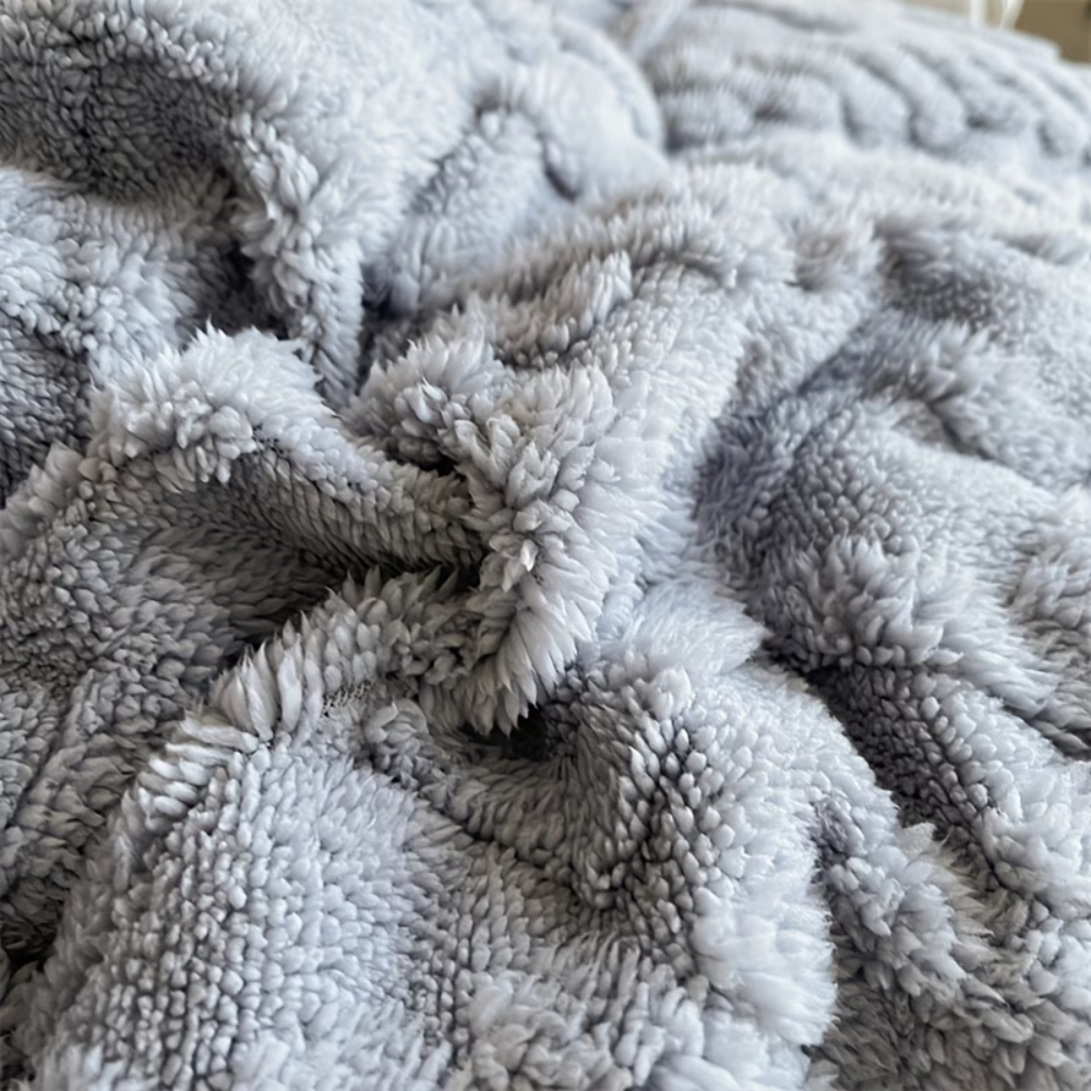 Nahaufnahme des flauschigen Plüschs der grauen Winterdecke