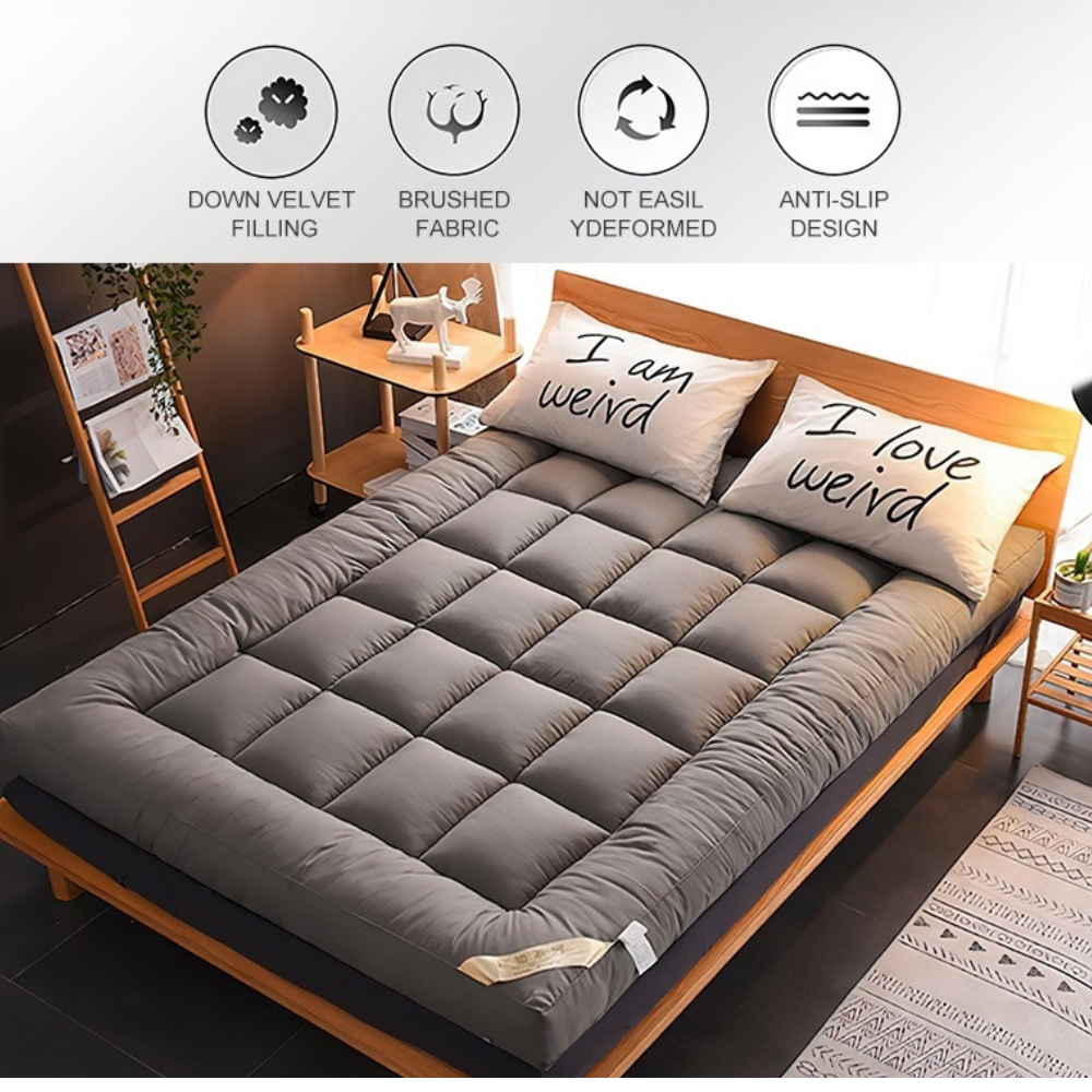Grauer gesteppter Matratzentopper auf dem Bett