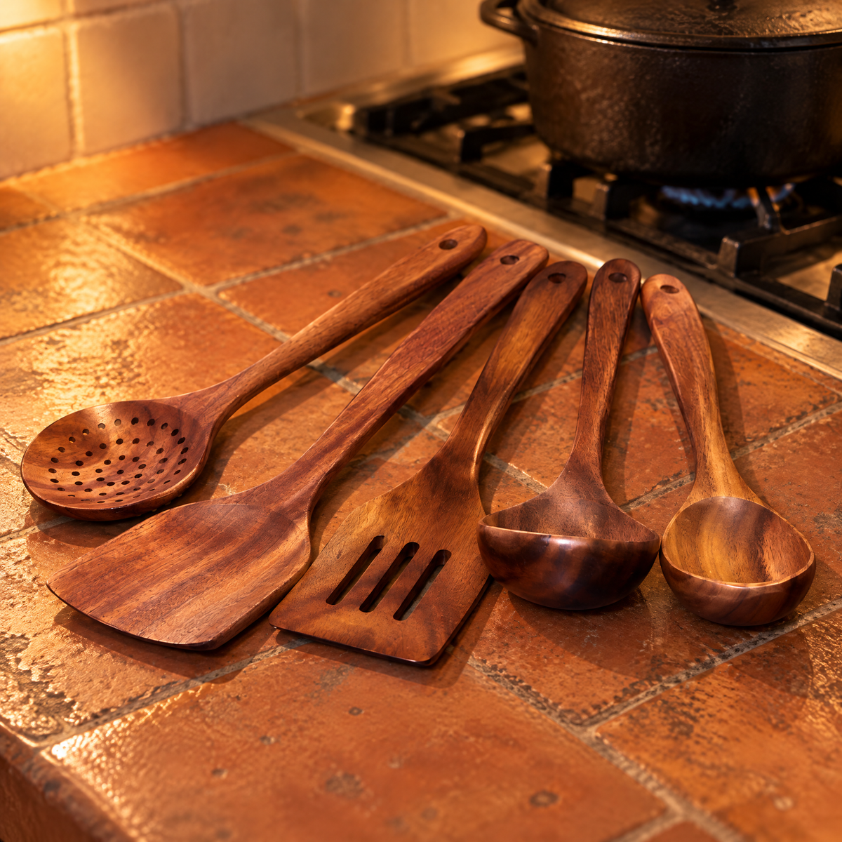 Küchenutensilien Set aus Holz, 5-teilig: Sieblöffel, Pfannenwender, Schlitzwender, Schöpflöffel und Kochlöffel auf Terrakottafliesen