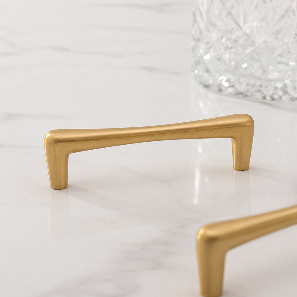 Goldener Möbelgriff in Tropfenform auf Marmor