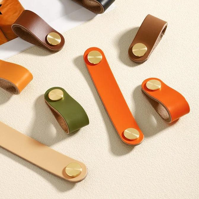 Möbelgriffe in Lederoptik in Orange, Olivgrün, Dunkelbraun, Hellbraun und Beige auf heller Fläche