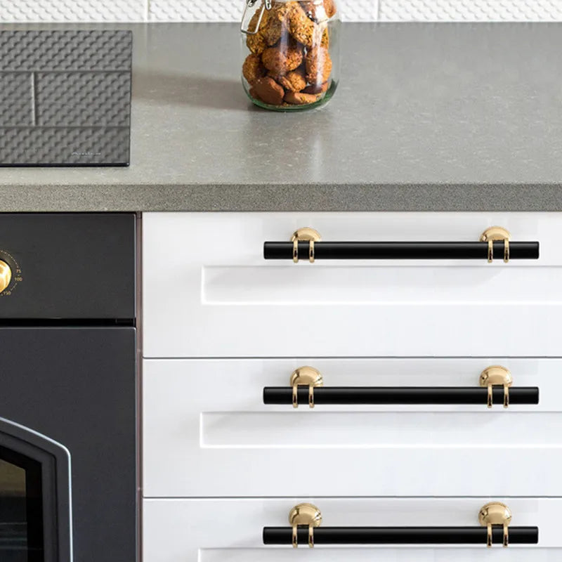 Schwarze Griffe mit Gold an weißen Küchenschubladen