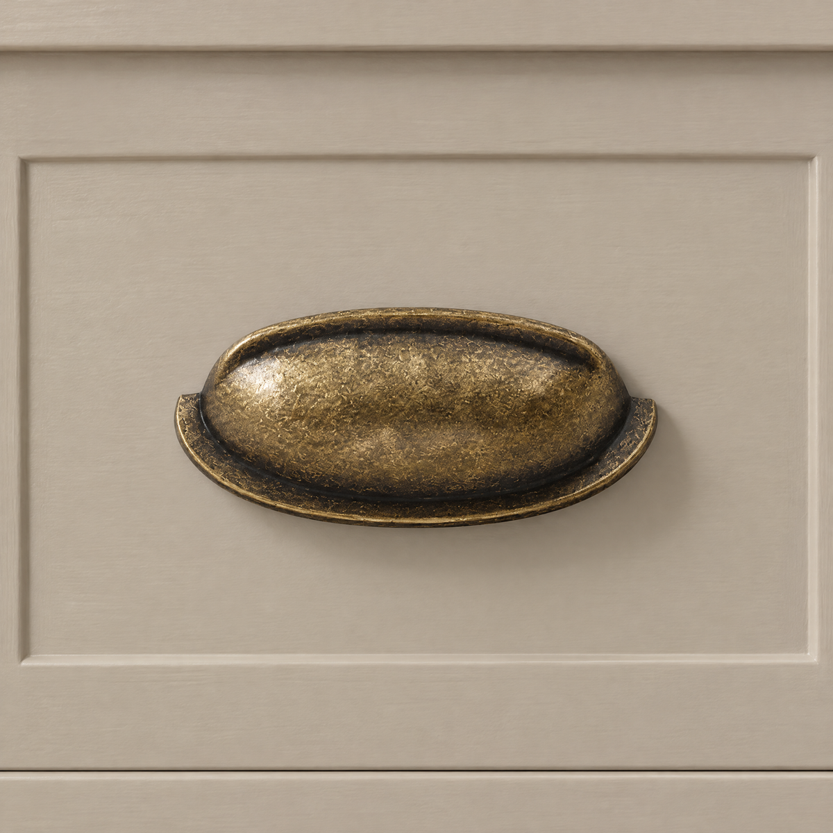 Muschelgriff in Antikbronze mit Lochabstand 76 mm an einer beigen Schublade