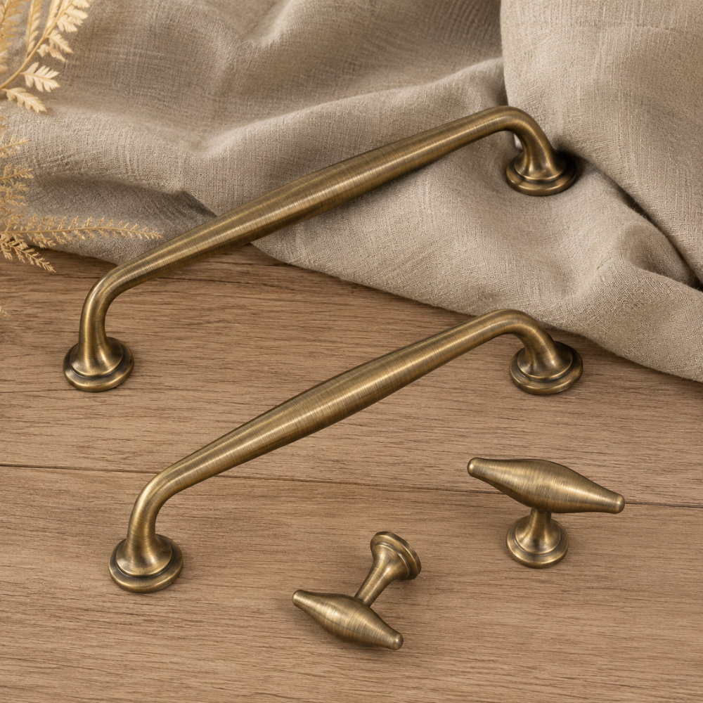 Geschwungene Möbelgriffe und T-Knöpfe in Antikbronze-Optik auf einem Holztisch
