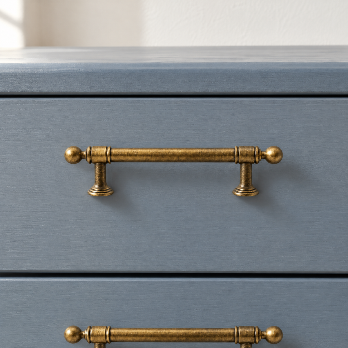 Möbelgriffe Vintage in Messingoptik mit Kugelenden auf einer graublau lackierten Kommodenschublade