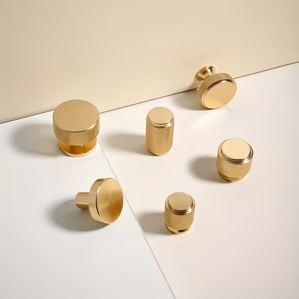 Goldene runde Möbelknöpfe in sechs Formen auf hellem Untergrund