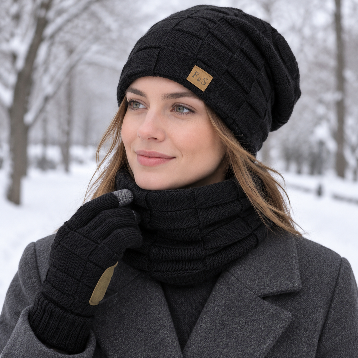 Frau im verschneiten Park mit schwarzem Mütze Schal Set: Beanie, Schlauchschal und Touchscreen Handschuhe