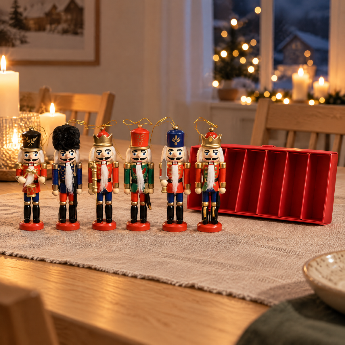 Sechs Nussknacker Figuren aus Holz in einer Reihe auf dem Esstisch neben der roten Box, Kerzenlicht am Abend