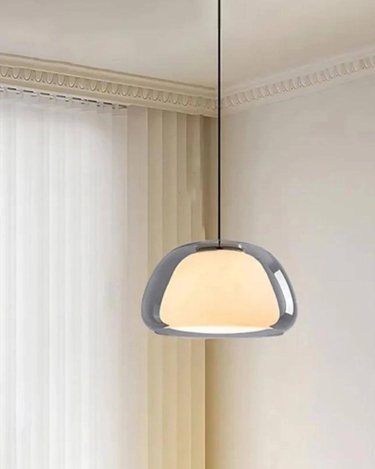 Pendelleuchte aus Rauchglas mit Opalglas vor hellen Vorhängen