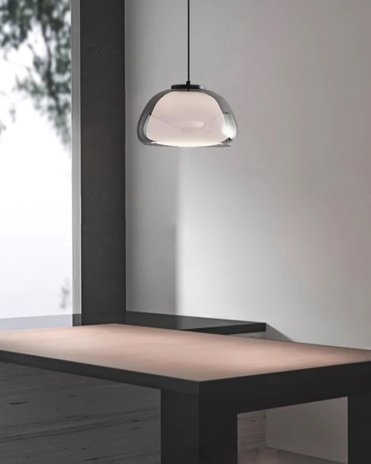 Pendelleuchte aus Rauchglas über einem dunklen Tisch