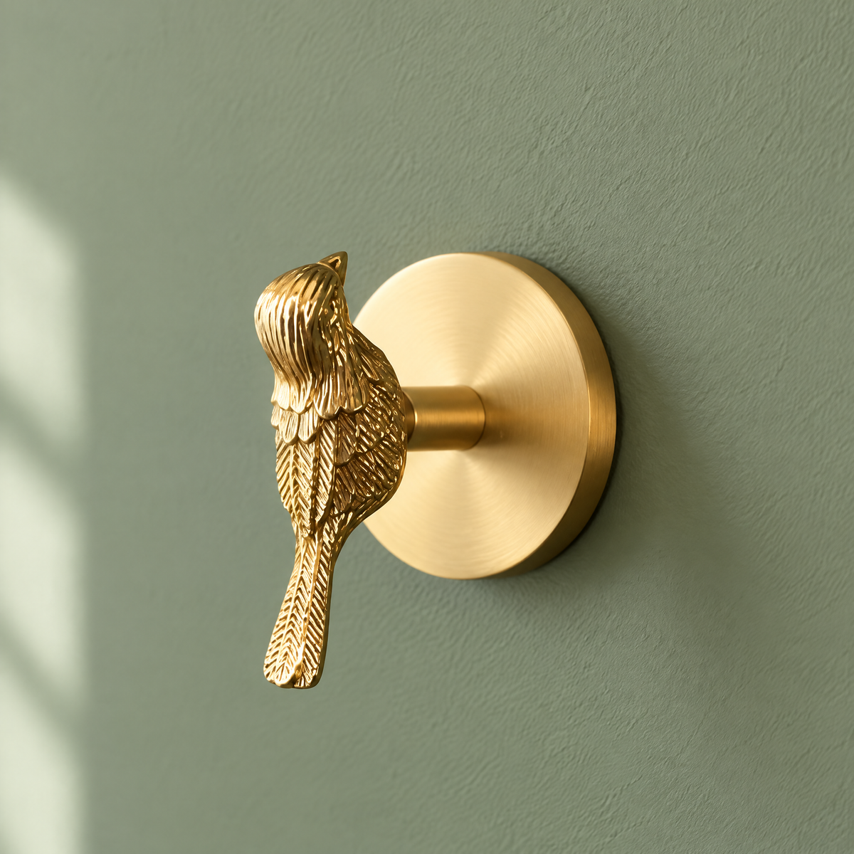 Garderobenhaken aus Messing mit goldenem Vogel an einer salbeigrünen Wand im Kinderzimmer