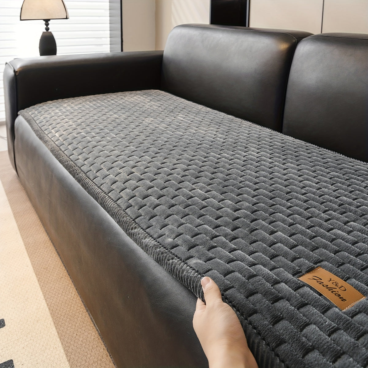 Sofa Überwurf in Dunkelgrau auf einem Ledersofa, Hand am Cord Rand