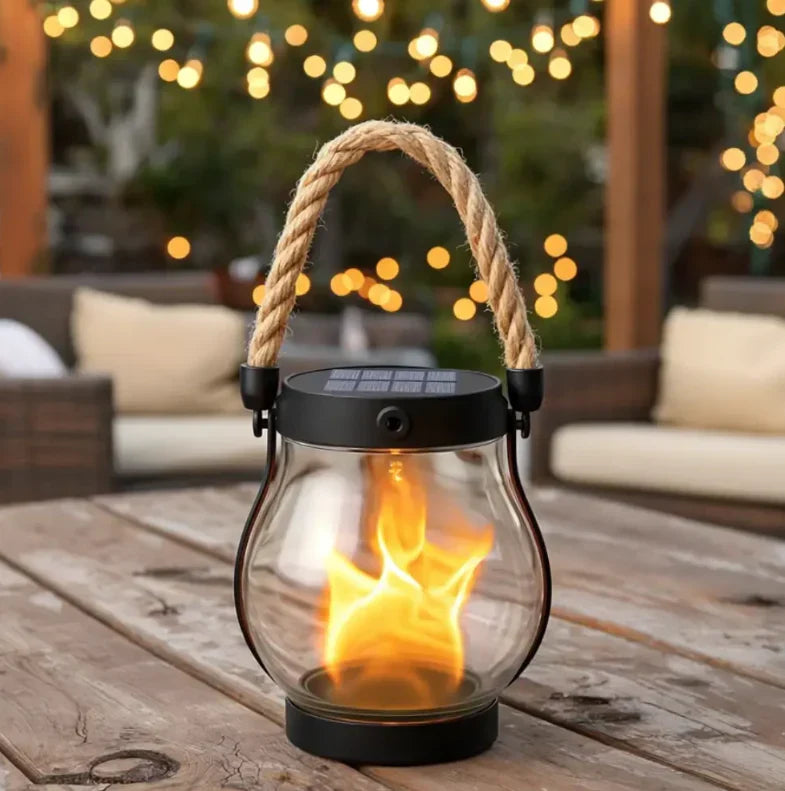 Solarlaterne mit klarem Glas auf einem Holztisch vor Lichterketten