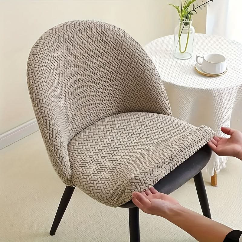 Stuhlhusse in Beige wird mit dem elastischen Saum unter den Sitz gezogen