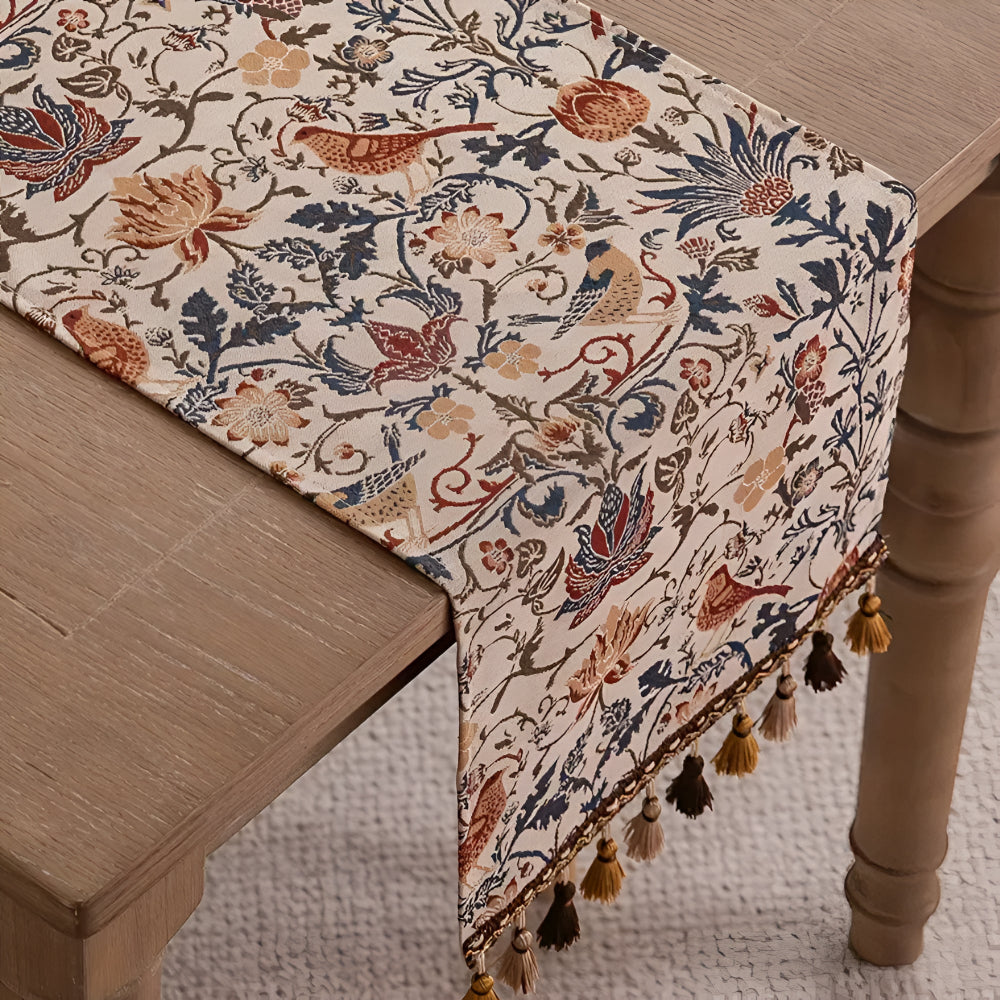 Tischläufer mit Blumenmuster und Quasten am Ende eines Holztisches