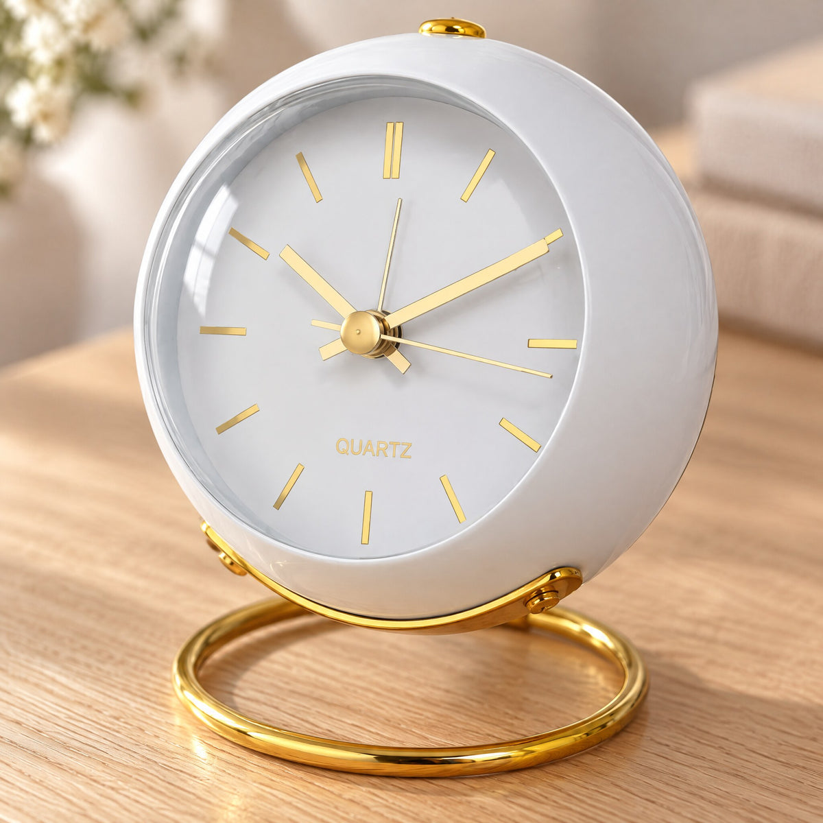 Nahaufnahme der weißen Tischuhr: goldene Zeiger, Glasfront und goldener Ringfuß