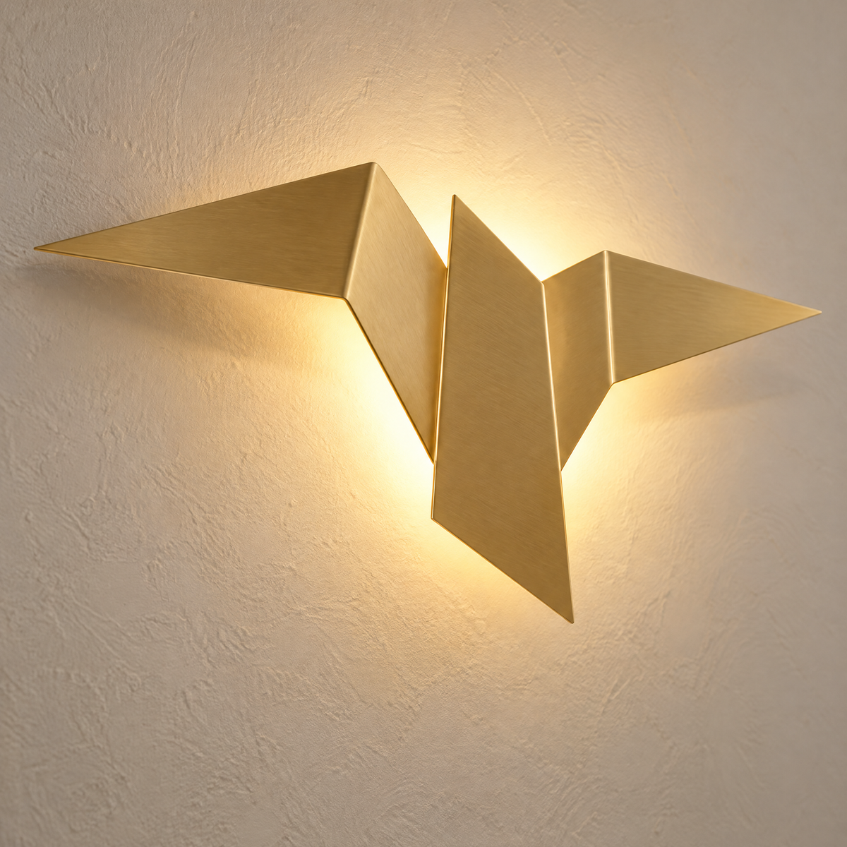 Nahaufnahme der goldenen Vogel Wandleuchte mit gefalteten Flügeln und warmem Lichtschein