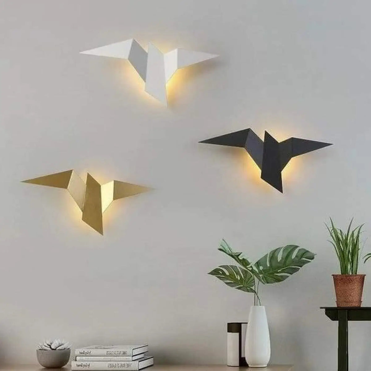 Wandleuchten in Vogelform in Weiß, Gold und Schwarz an einer Wand im Wohnzimmer