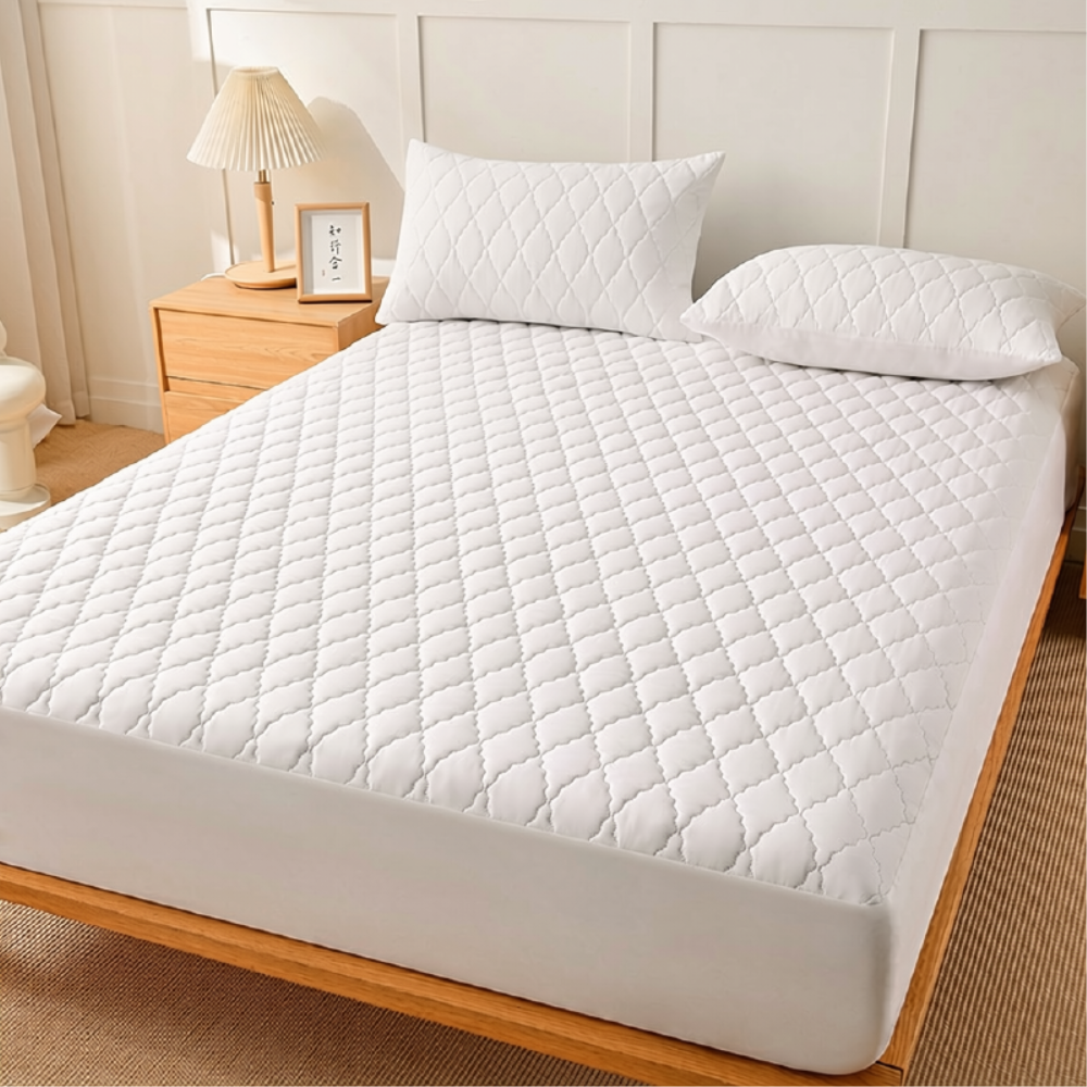 Weißer gesteppter Matratzenschoner auf dem Bett im Schlafzimmer