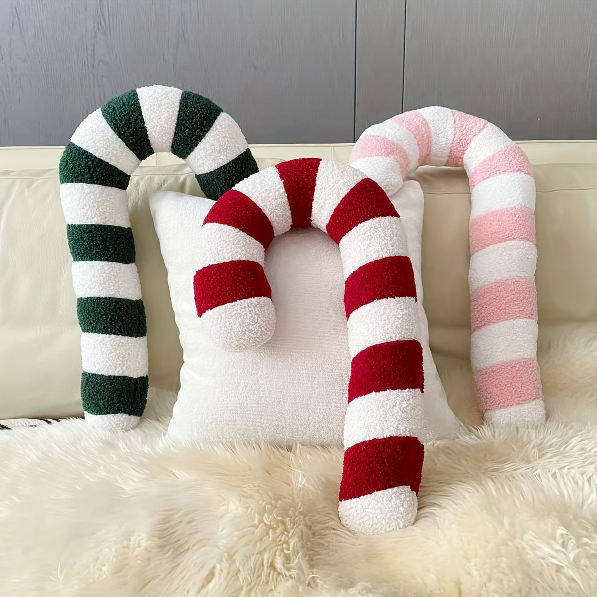 Zuckerstange Kissen in Grün, Rot und Rosa auf einem Sofa mit Fellteppich